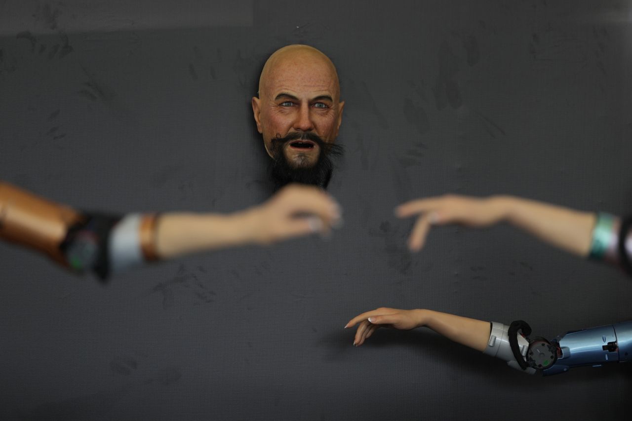 A robot face capable of mimicking human-like expressions is displayed near robotic arms at the World Robot Conference in Beijing on Wednesday, August 16.