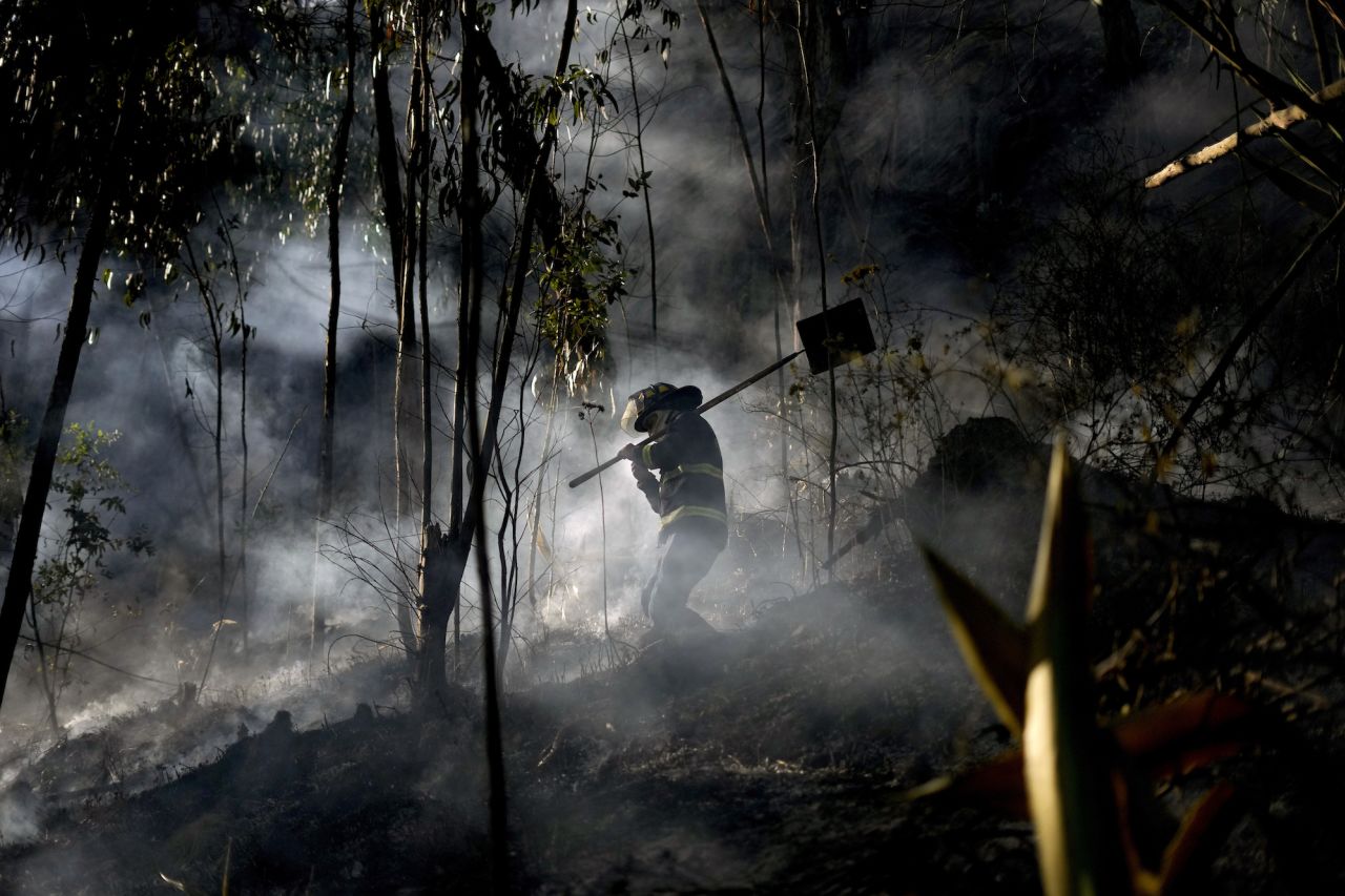 A firefighter walks through the smoke of a mountain fire in Soacha, Colombia, on August 14.