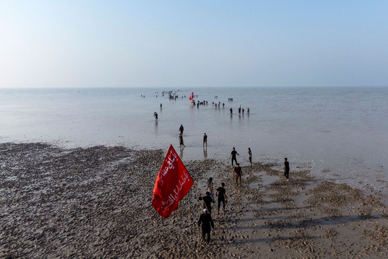 Shiite Muslim pilgrims wave flags as they start marching from Al-Faw, Iraq, toward Karbala, Iraq, ahead of the Arba'een religious festival on Sunday, August 13.