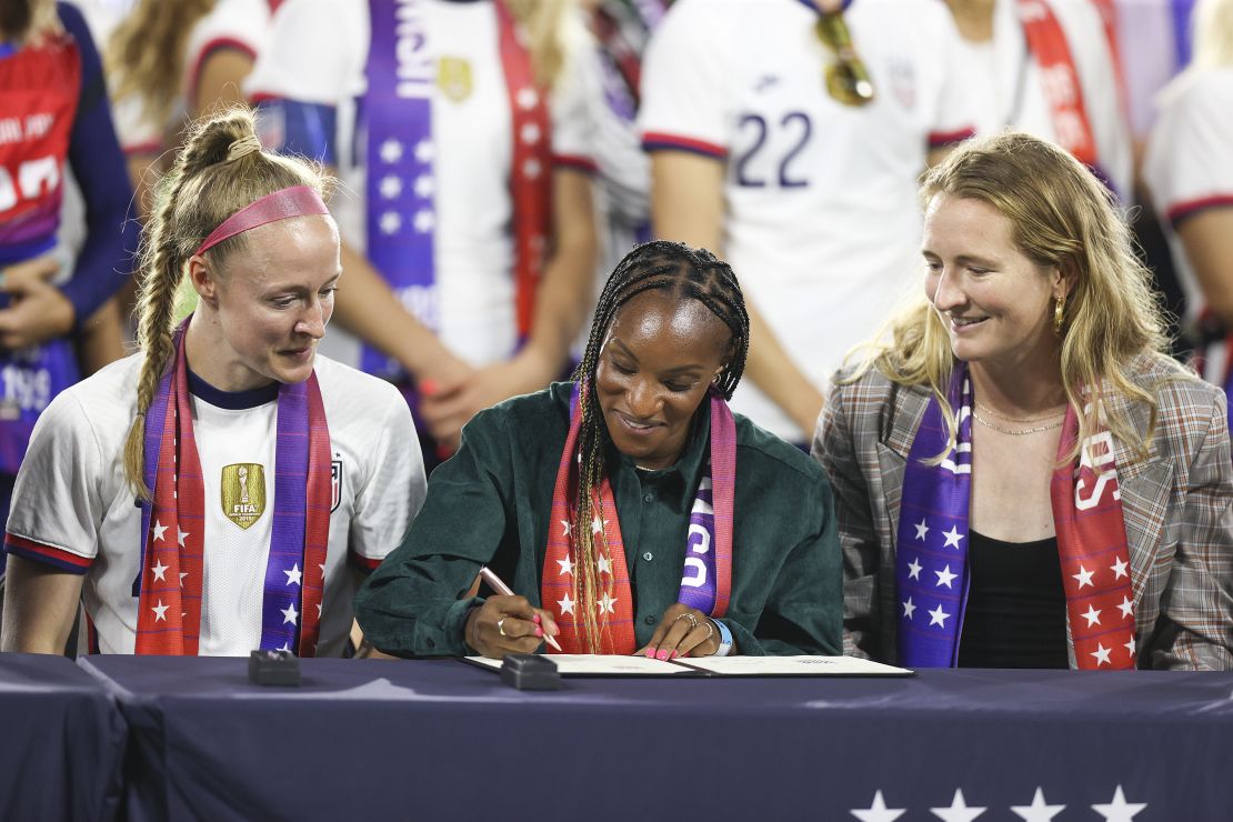 Crystal Dunn (middle) signs a collective bargaining agreement signing signifying equal pay between the US men's and women's national soccer teams on September 6, 2022 in Washington, DC. 