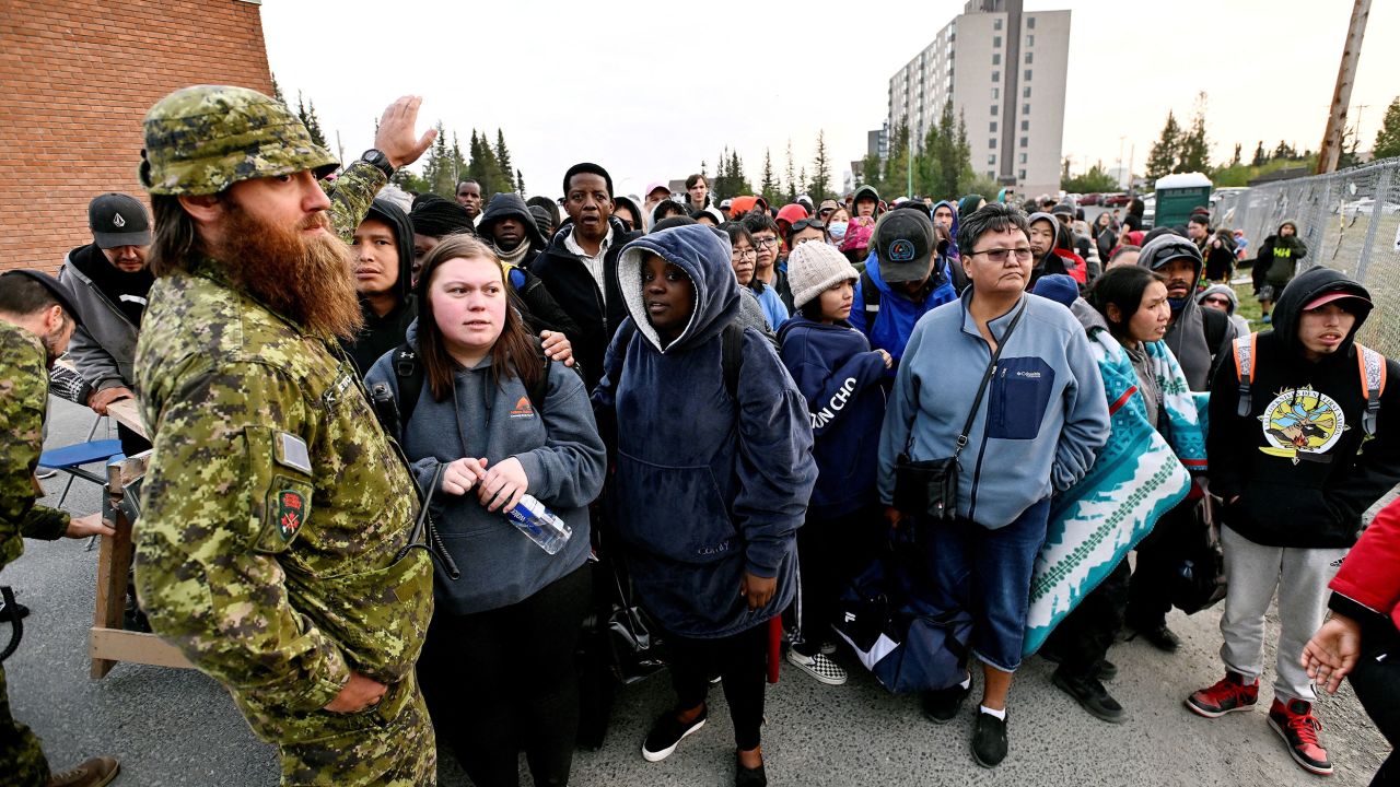 Mensen staan ​​in de rij voor een school om geëvacueerd te worden in Yellowknife.     