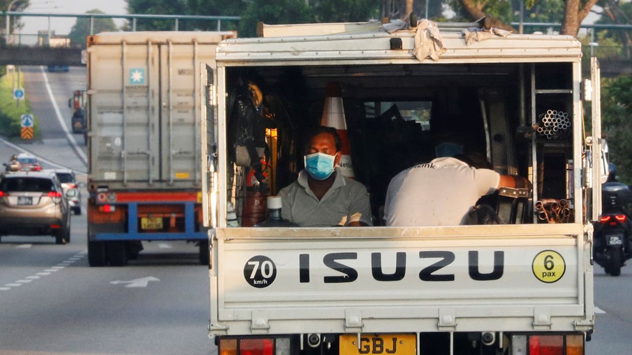 Migrant workers sit in the back of a lorry in Singapore on May 15, 2020. 