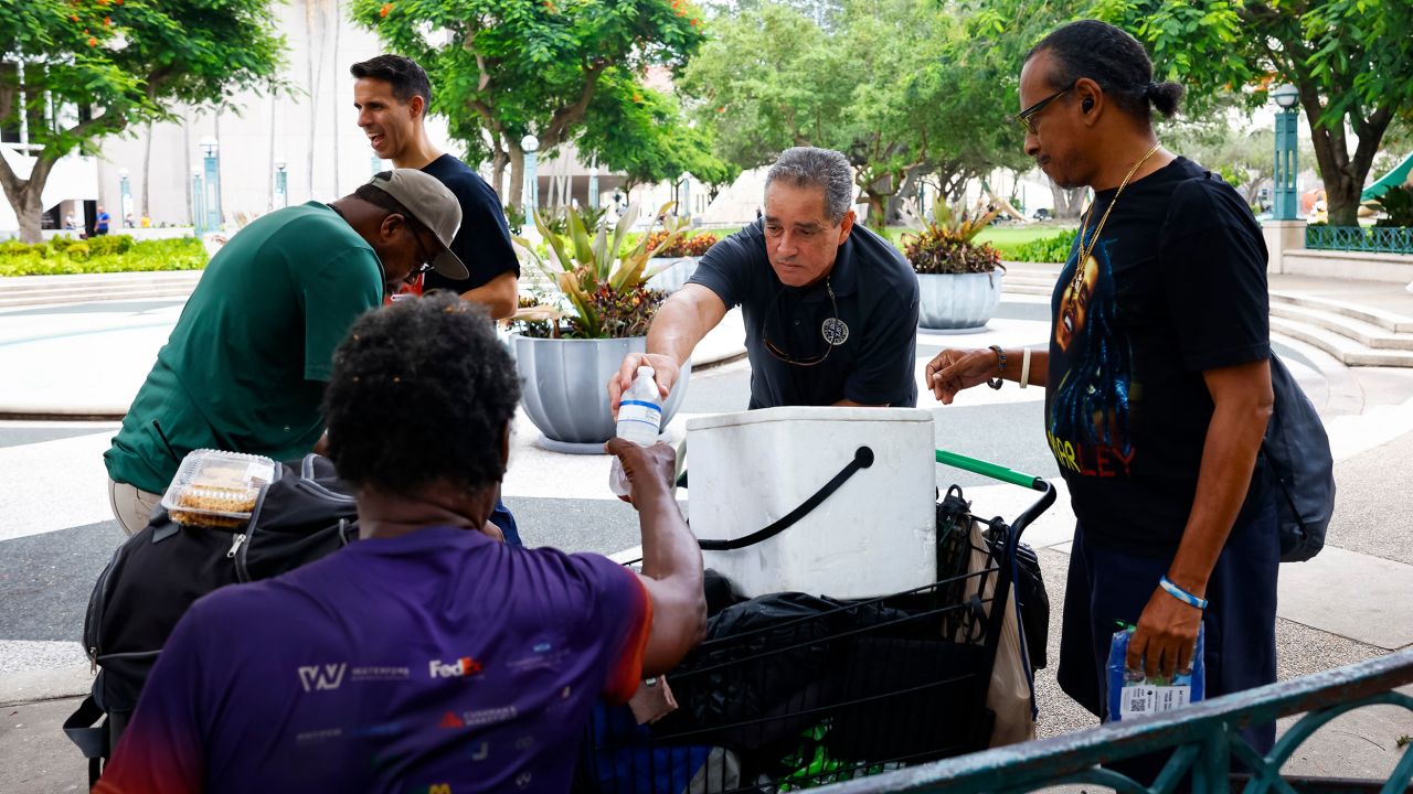 Miami-Dade County Homeless Trust representatives distribute bottles of water and shelter information during a heat wave in Miami, Florida, on July 25, 2023.