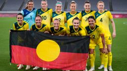 The Matildas pose for a photo with the Aboriginal flag before playing New Zealand at the 2020 Summer Olympics, July 21, 2021, in Tokyo. 