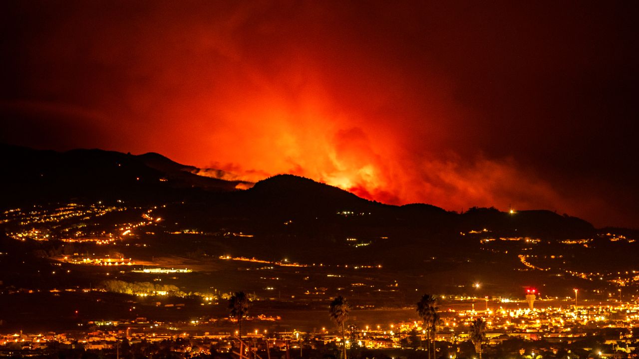  На хоризонта се виждат факли, докато огънят напредва през гората към град Ла Лагуна и летище Лос Родеос. class=