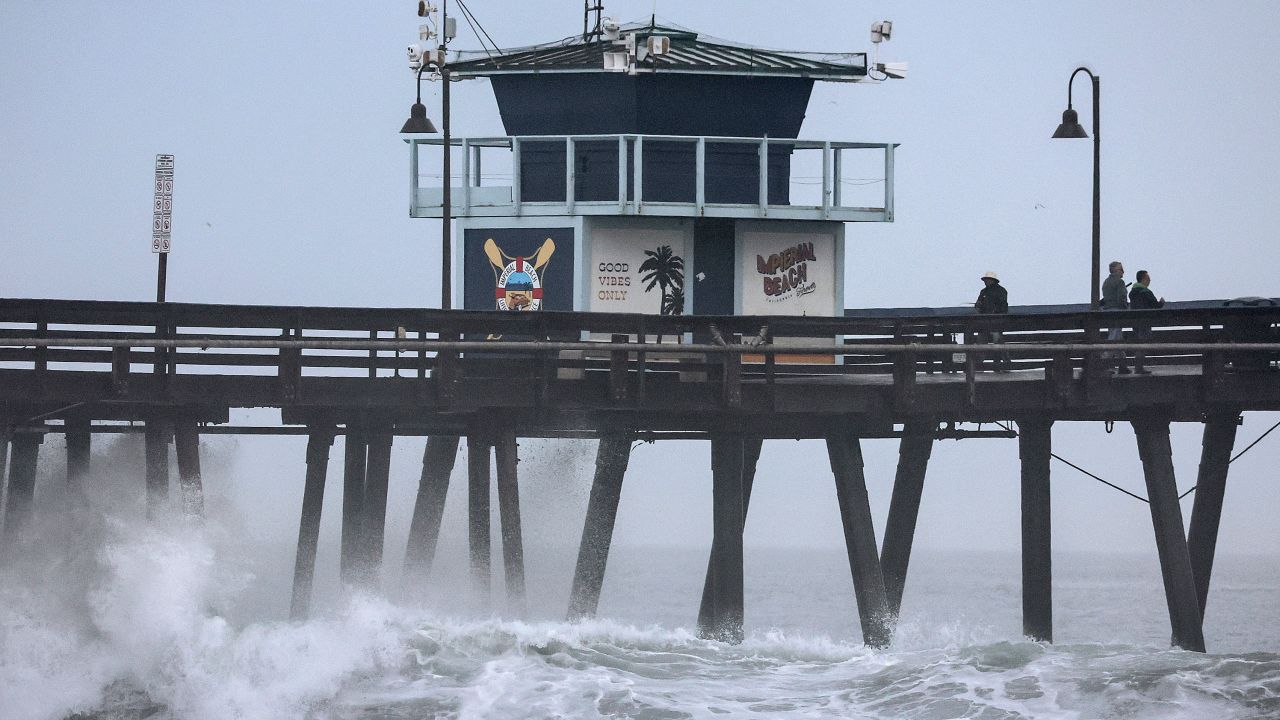 People stand on an Imperial Beach, California, pier in San Diego County on Sunday as Tropical Storm Hilary heads for the Southwest US. 