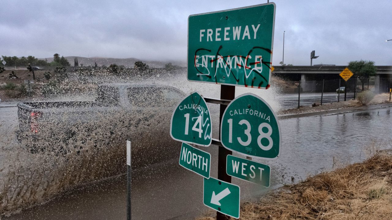 A submerged car drives through a flooded highway entrance in Palmdale, California. 