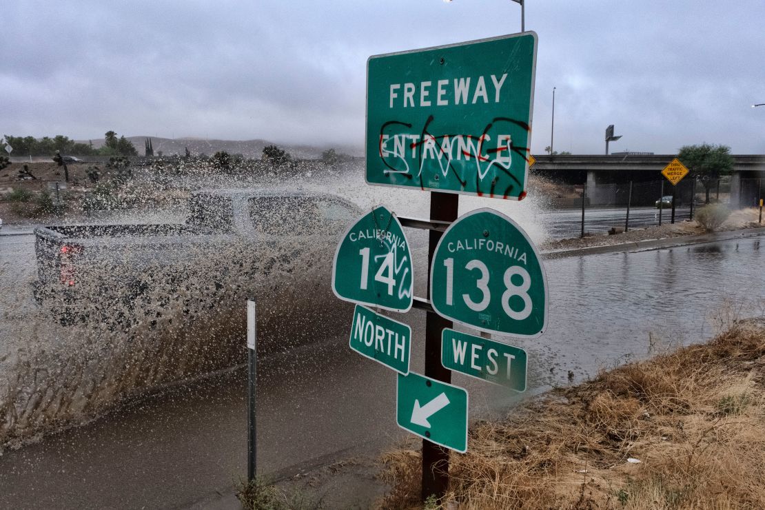 A vehicle engulfed in water drives through a flooded freeway entrance in Palmdale, California. 