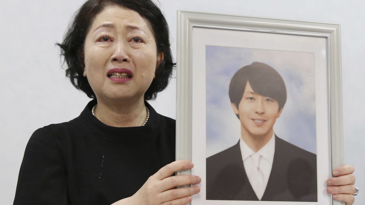 Junko Takashima, the mother of Shingo Takashima, a doctor who died by suicide last year, holds up his photo at a news conference in Osaka, Japan, on August 18, 2023.