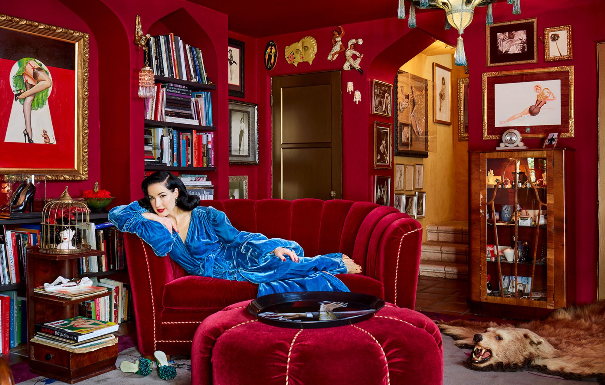 The red room is Von Teese's library. Built-in shelves, designed to mirror the room's preexisting Moorish archways, were added in order to house the star's extensive book collection. (She's a bestselling author herself; Von Teese's latest book, a style guide entitled Fashioning the Femme Fatale, is due next year.) The room showcases a lot of Von Teese's extensive antiques collection—"things were just made more beautifully back then"—but the couch is a reproduction. "I didn't have room for a full-size Art Deco couch, so we created something with a '30s look, but on a smaller scale," she says. Von Teese wears one of her favorite pieces of vintage loungewear, which she happens to collect. "This one's really extravagant," she says. "It has a long train and these long balloon sleeves, and you just can't help but wonder why. Maybe it was made for a movie or something."(Architectural Digest)