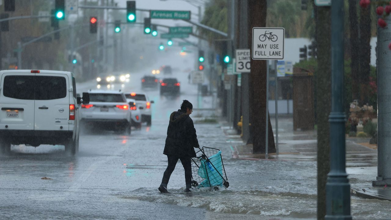 A person pushes a cart on a flooded street as Tropical Storm Hilary heads north near Palm Springs, California, on August 20, 2023.