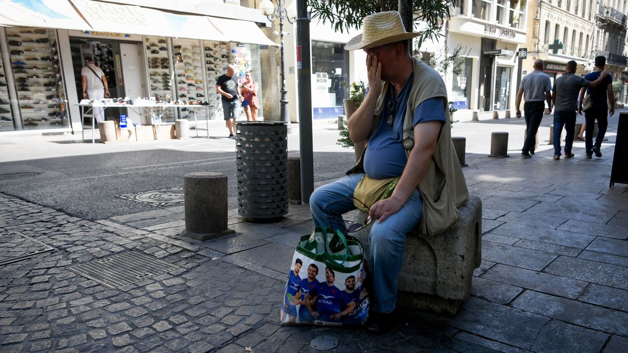 A man wipes off sweat and rests during a heatwave. Météo-France has issued red-level heat alerts for four departments in France.