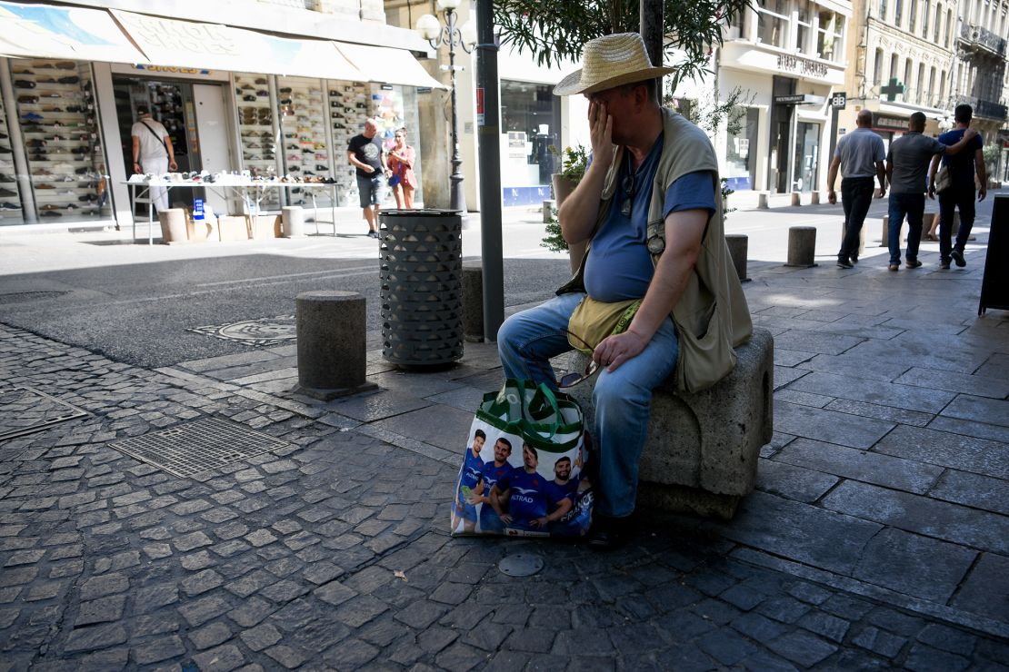 A man wipes off sweat and rests during a heatwave. Météo-France has issued red-level heat alerts for four departments in France.