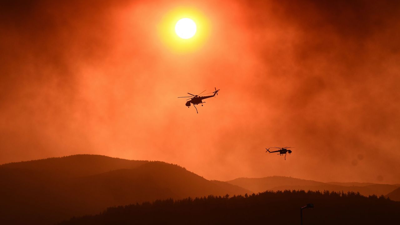 Helicopters fly over as wildfire rages near Alexandroupoli, northern Greece, on August 21, 2023. The European Union announced it was deploying two Cyprus-based fire-fighting aircraft and a Romanian fire-fighting team via the bloc's civil protection mechanism, as wildfires rage uncontrolled in Greece for a third day. (Photo by Sakis MITROLIDIS / AFP) (Photo by SAKIS MITROLIDIS/AFP via Getty Images)