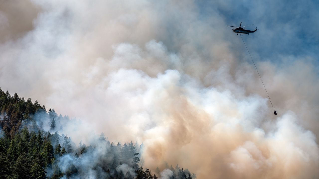 A helicopter waterbomber flies above the Cameron Bluffs wildfire near Port Alberni, British Columbia, Canada, on Tuesday, June 6, 2023.