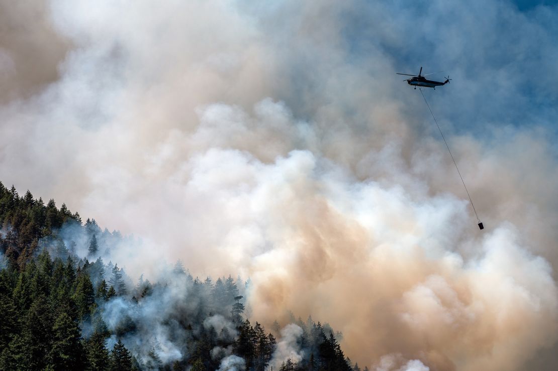A helicopter waterbomber flies above the Cameron Bluffs wildfire near Port Alberni, British Columbia, Canada, on Tuesday, June 6, 2023. 