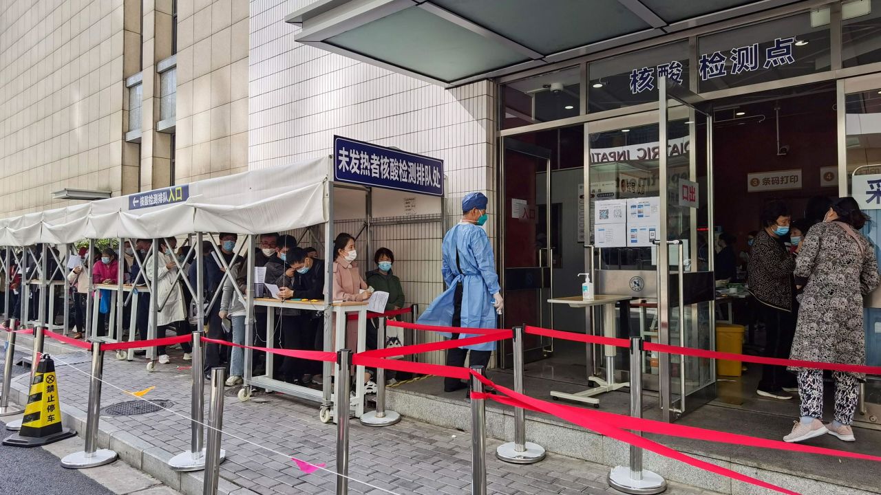Un trabajador médico junto a personas que hacen fila para hacerse la prueba de Covid-19 en un hospital de Shanghai en 2020.