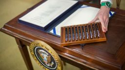 Служител на Белия дом подрежда химикалки преди подписване на законопроект през 2016 г.