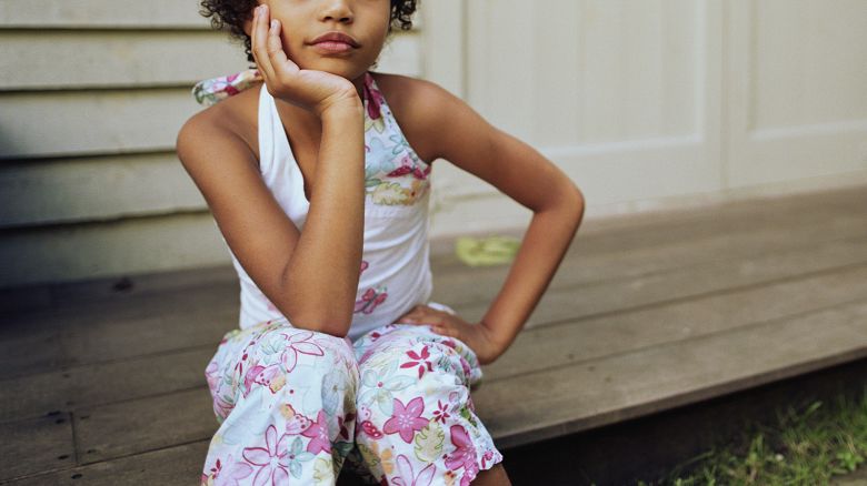 Girl (6-8) sitting on porch step, portrait