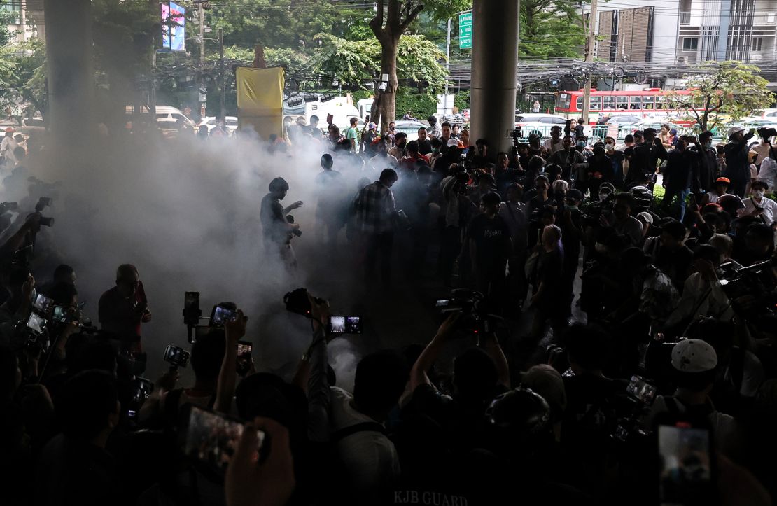 Protesters walk through smoke after setting fire to mock corpses during a protest at Pheu Thai Party headquarters in Bangkok on August 2, 2023.
