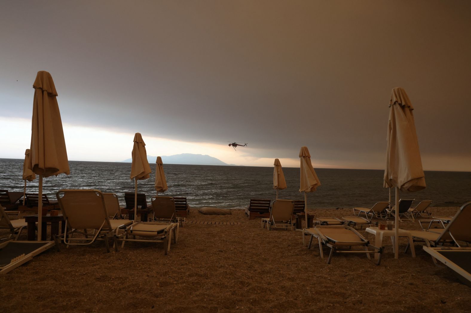 A firefighting helicopter prepares to refill water as a wildfire burns in the village of Dikella on August 22.