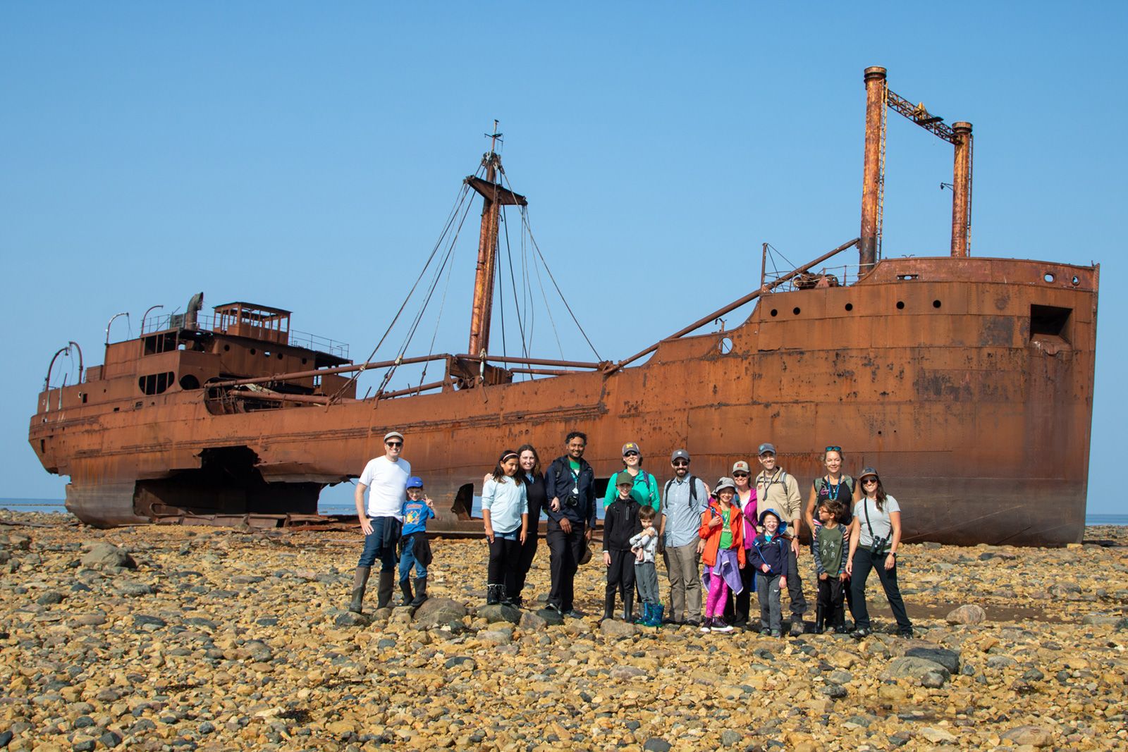 A group of parents and children on a tour with Frontiers North Adventures walks to the wreck of the Ithaca.