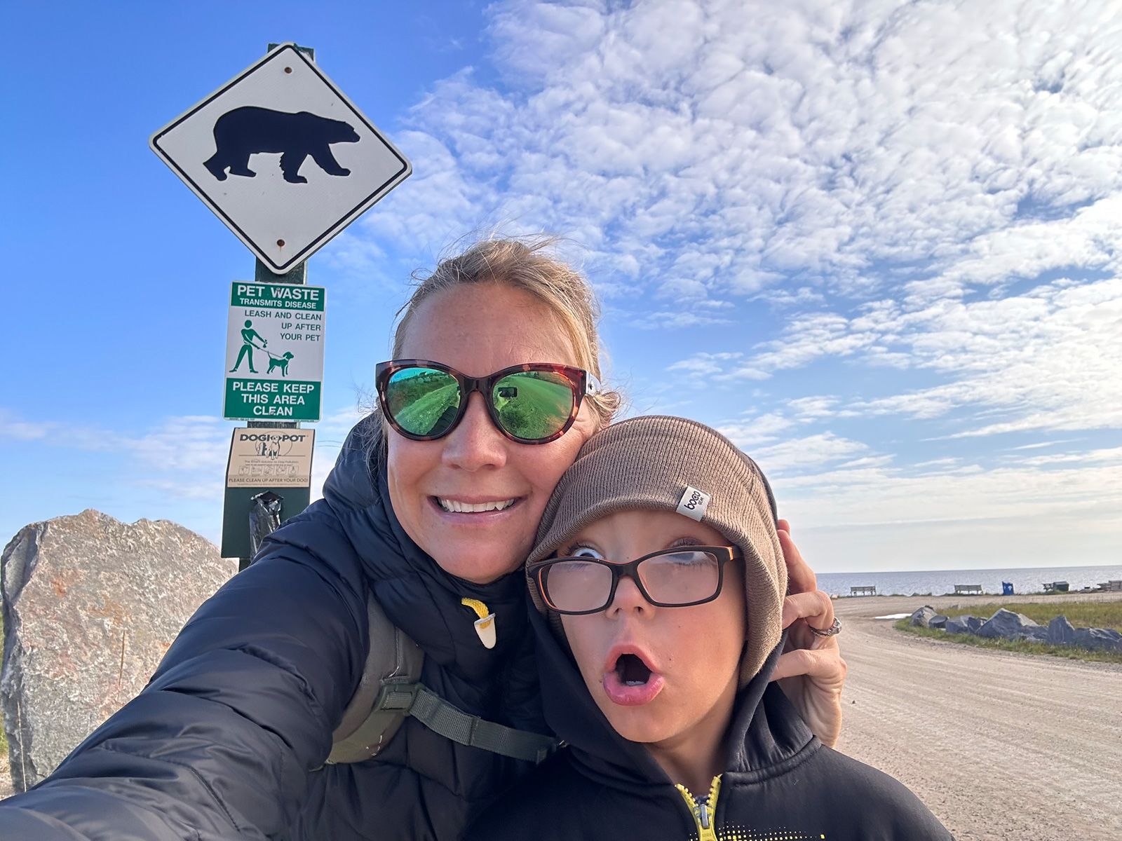 Terry Ward and her son take a selfie in front of a warning sign near Churchill’s city beach, fronting Hudson Bay.