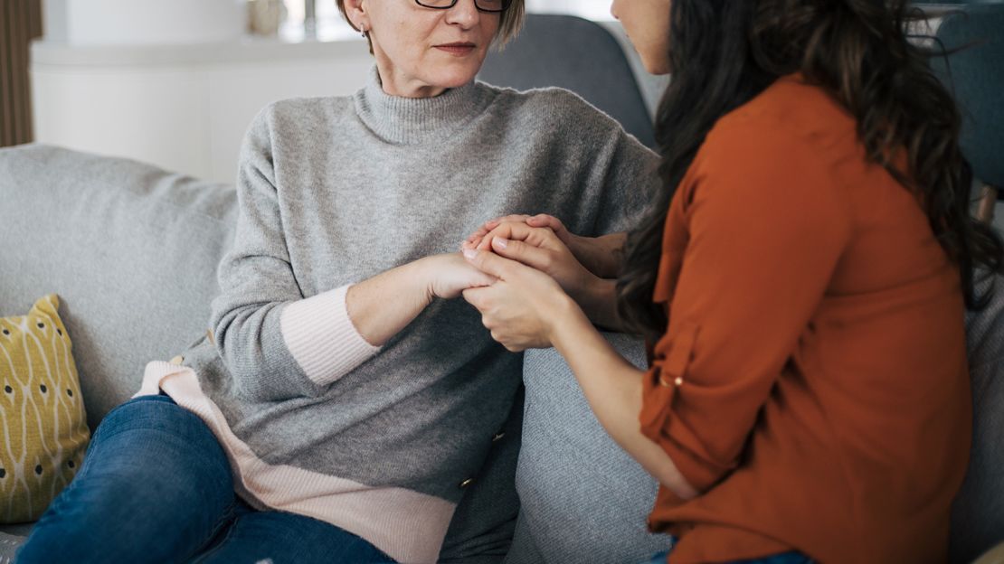 Mother and daughter talking to each other and holding hands