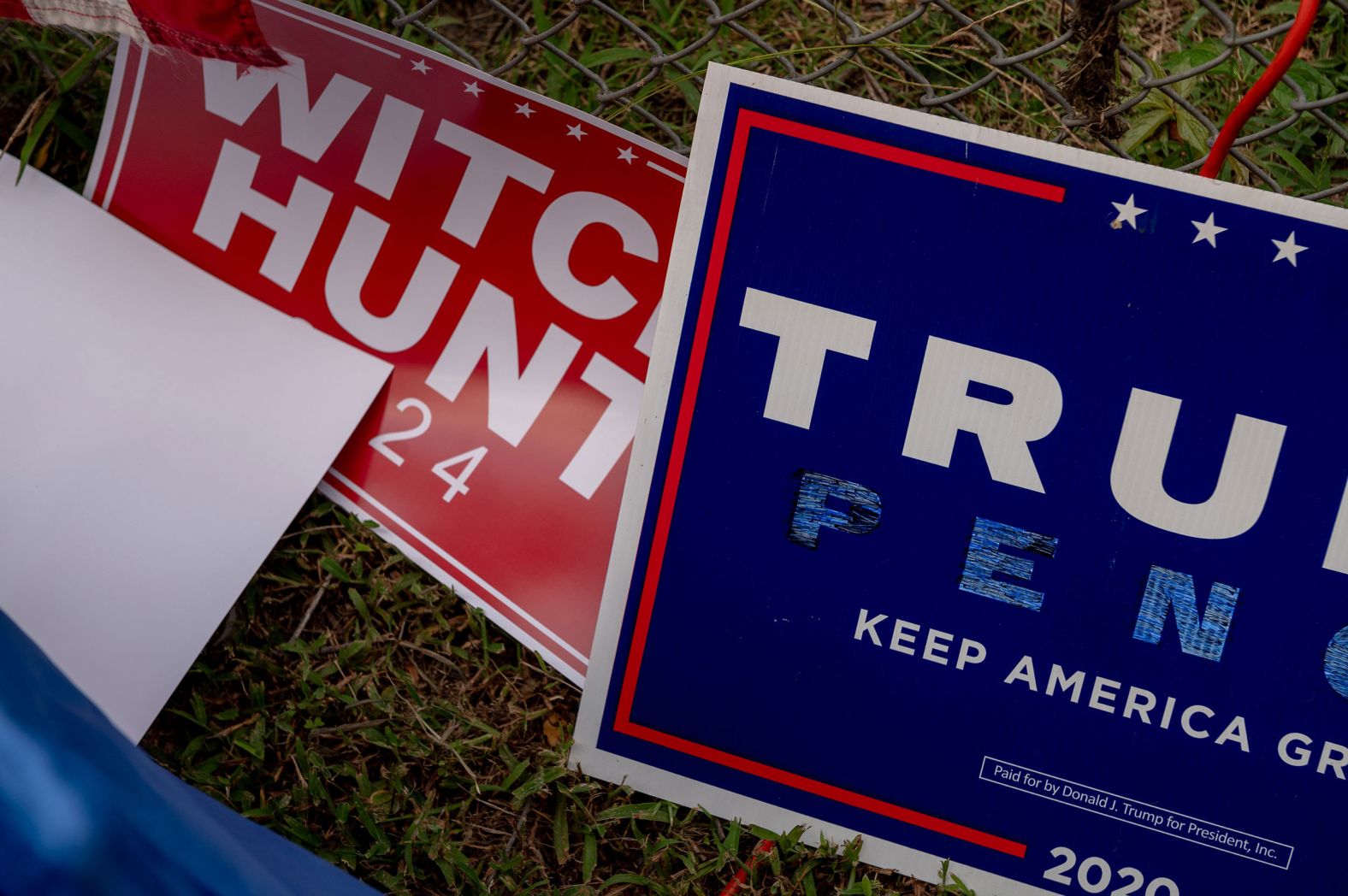 Trump signs sit in the grass against a fence outside of the jail on Thursday.