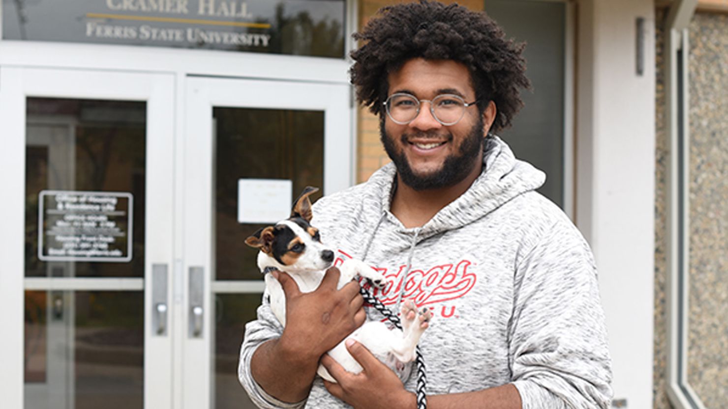 Ferris State University student Alando Steele, holding his puppy Emi, is all smiles about a new pet-friendly floor in Cramer Hall.