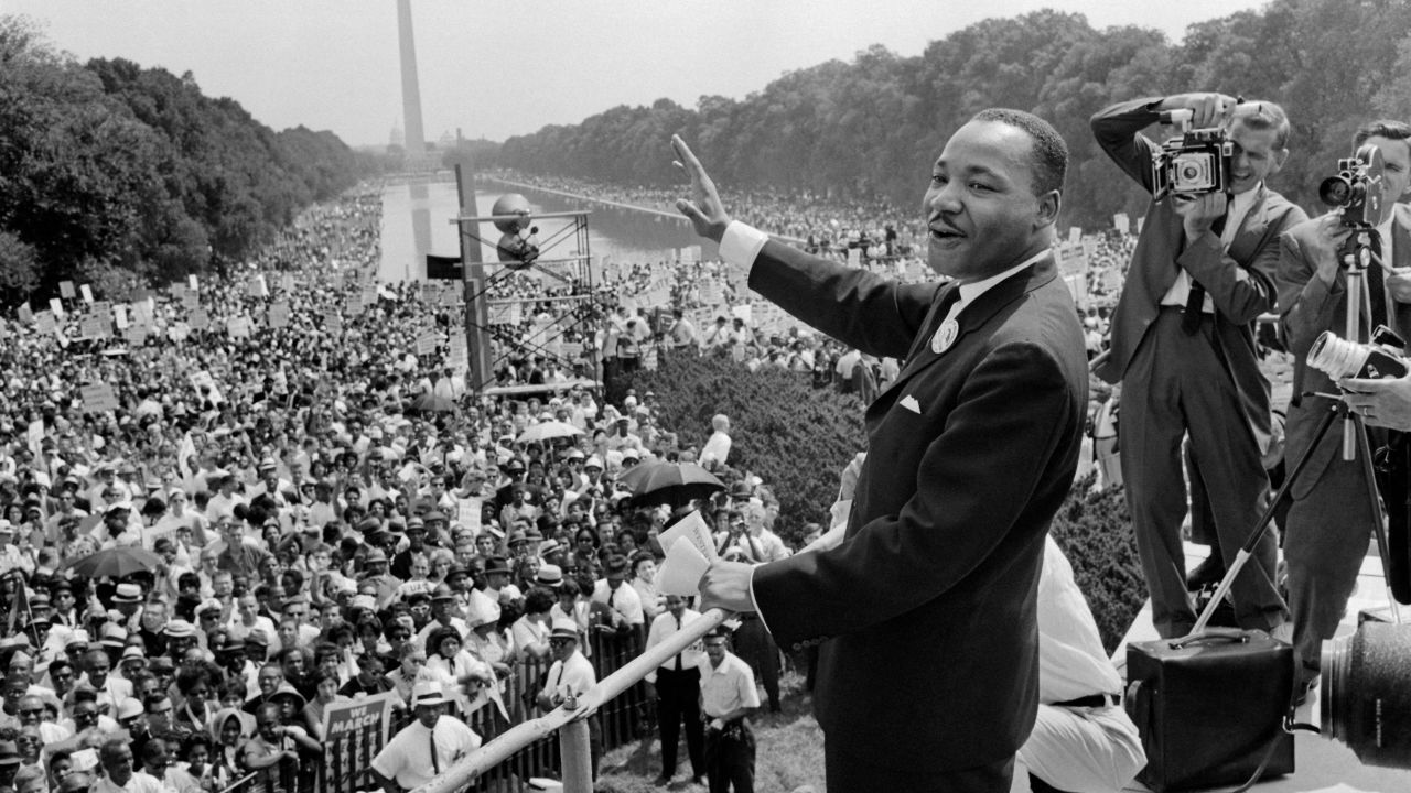 TOPSHOT - US civil rights leader Martin Luther King (C) waves to supporters 28 August 1963 on the Mall in Washington DC (Washington Monument in background) during the 