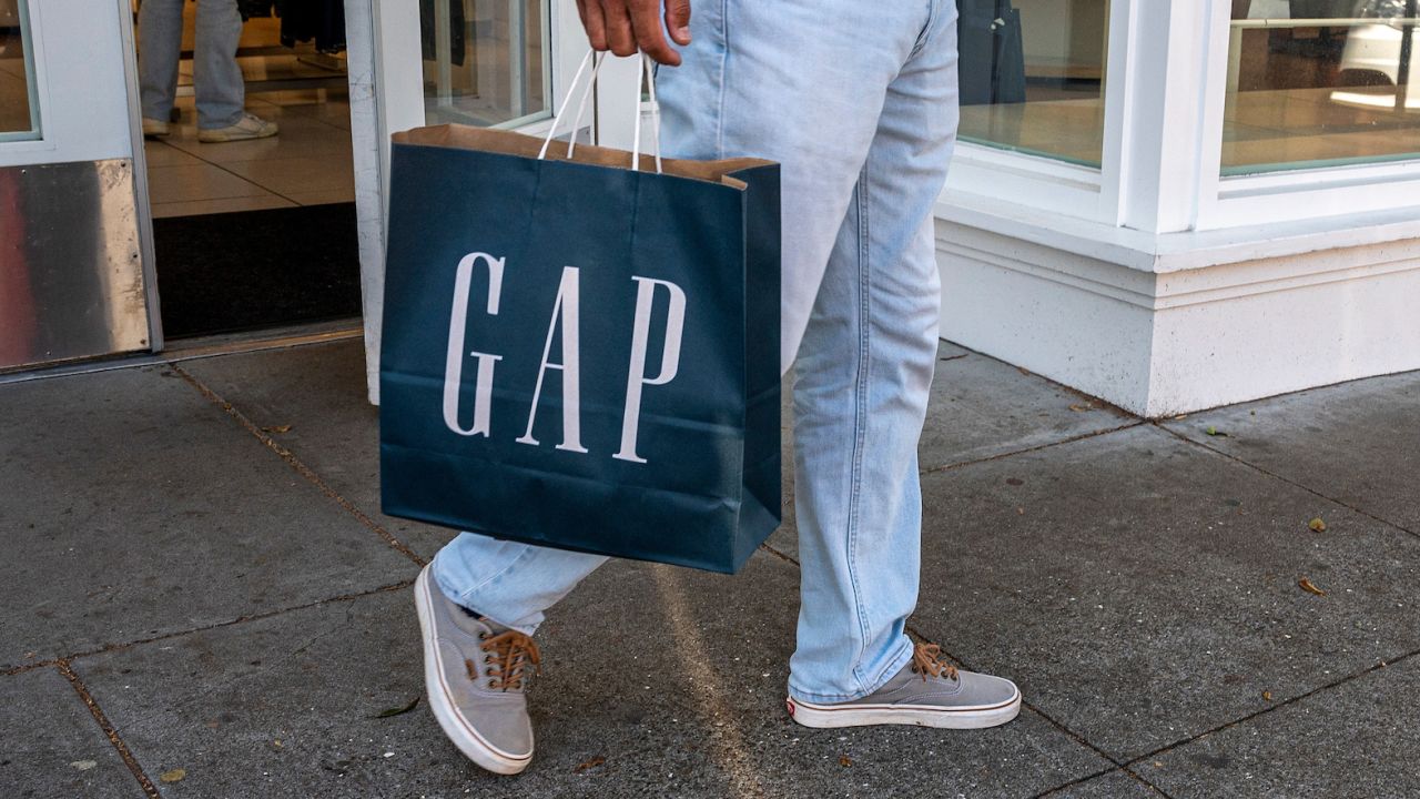 A shopper carries a Gap bag outside a store in San Francisco, California, US, on Thursday, April 27, 2023.  Photographer: David Paul Morris/Bloomberg