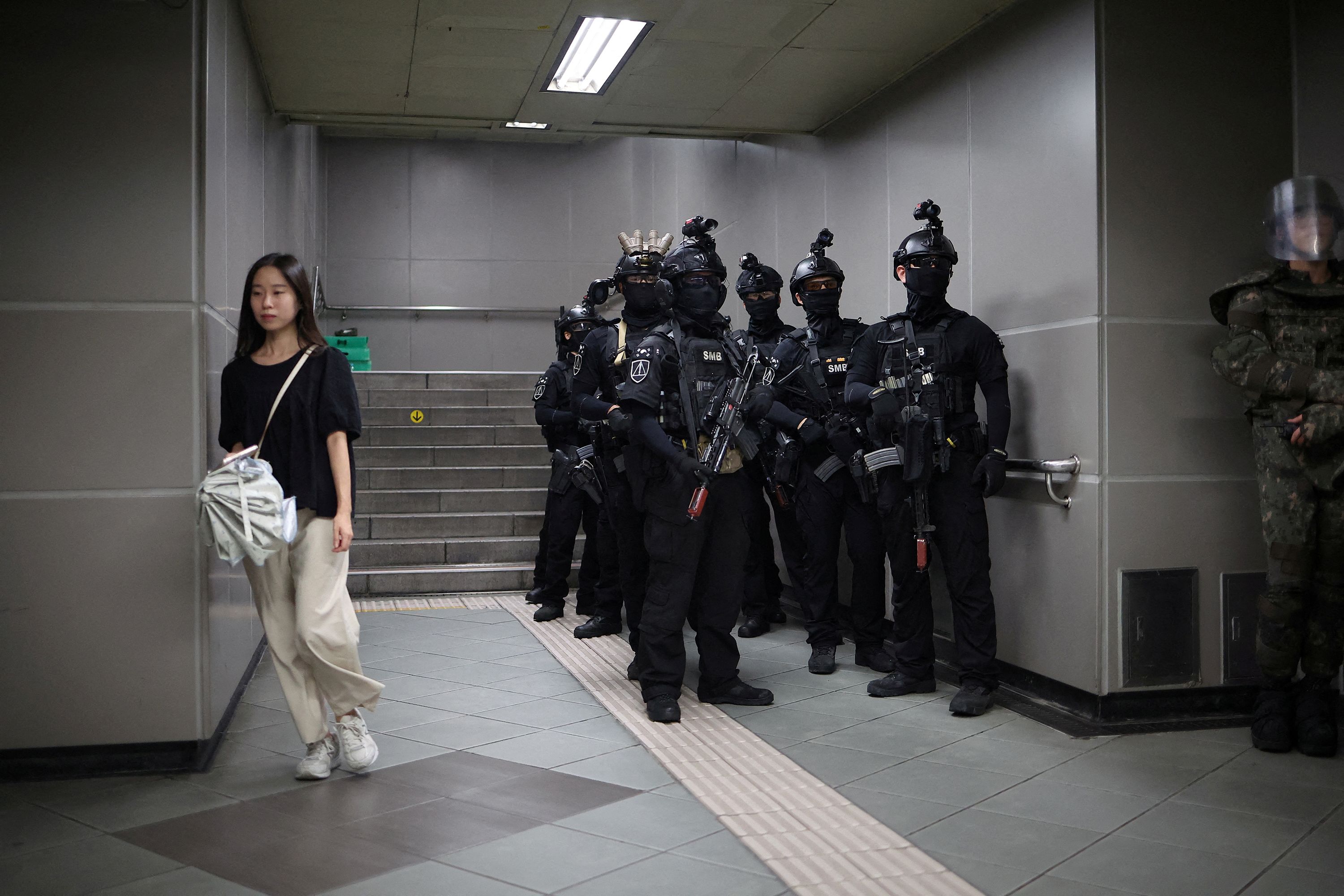 A woman walks past soldiers taking part in an anti-terror drill at a subway station in Seoul, South Korea, on Tuesday, August 22.