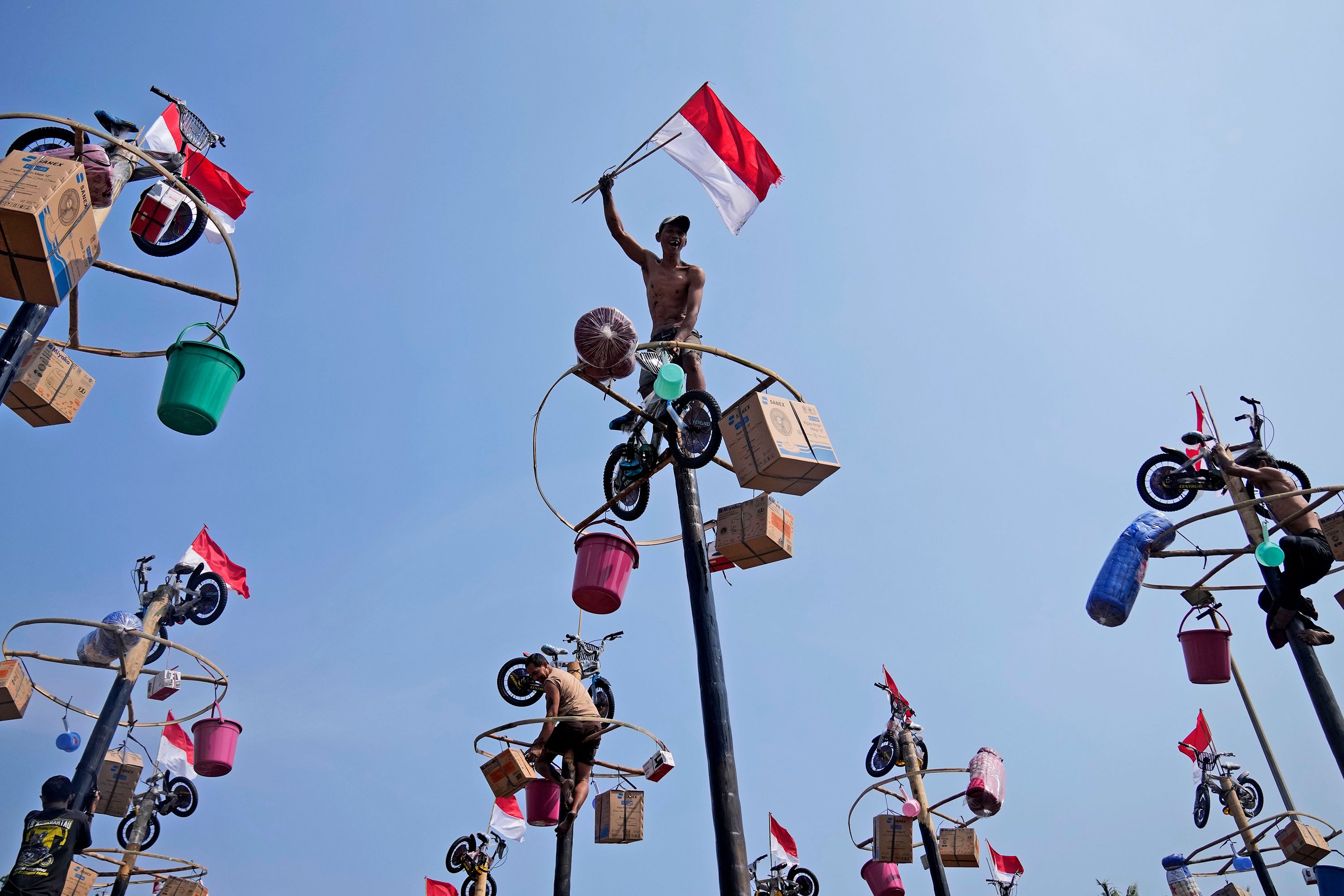 A participant celebrates after reaching the prizes during a greased-pole climbing competition in Jakarta, Indonesia, on Thursday, August 17. It was part of the country's Independence Day celebrations at Ancol Beach.