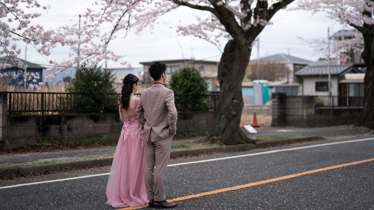 A couple poses for a wedding photograph near blossoming cherry trees in the Yonomori area of Fukushima, Japan, on April 2, 2023.