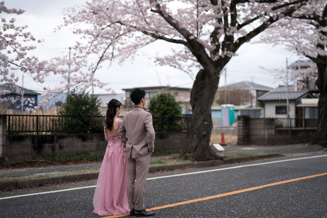 TOMIOKA, JAPAN - APRIL 02: A couple poses for a wedding photograph near cherry trees in bloom in the Yonomori area on April 02, 2023 in Tomioka, Fukushima, Japan. The evacuation order for the Yonomori area was lifted on April 1 for the first time in twelve years since the area was designated as a "difficult-to-return" zone following the Fukushima Dai-ichi nuclear power plant disaster in 2011. (Photo by Tomohiro Ohsumi/Getty Images)