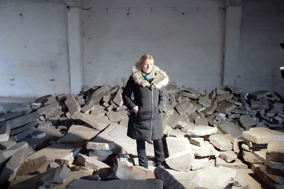 Debra Brunner of The Together Plan stands in a warehouse in Brest, surrounded by the broken headstones.