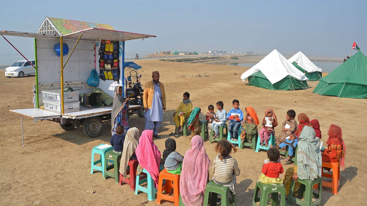 Internally displaced flood-affected children attend a mobile school class near makeshift camp in the flood-hit area of Dera Allah Yar in Jaffarabad district of Balochistan province on January 9, 2023. 