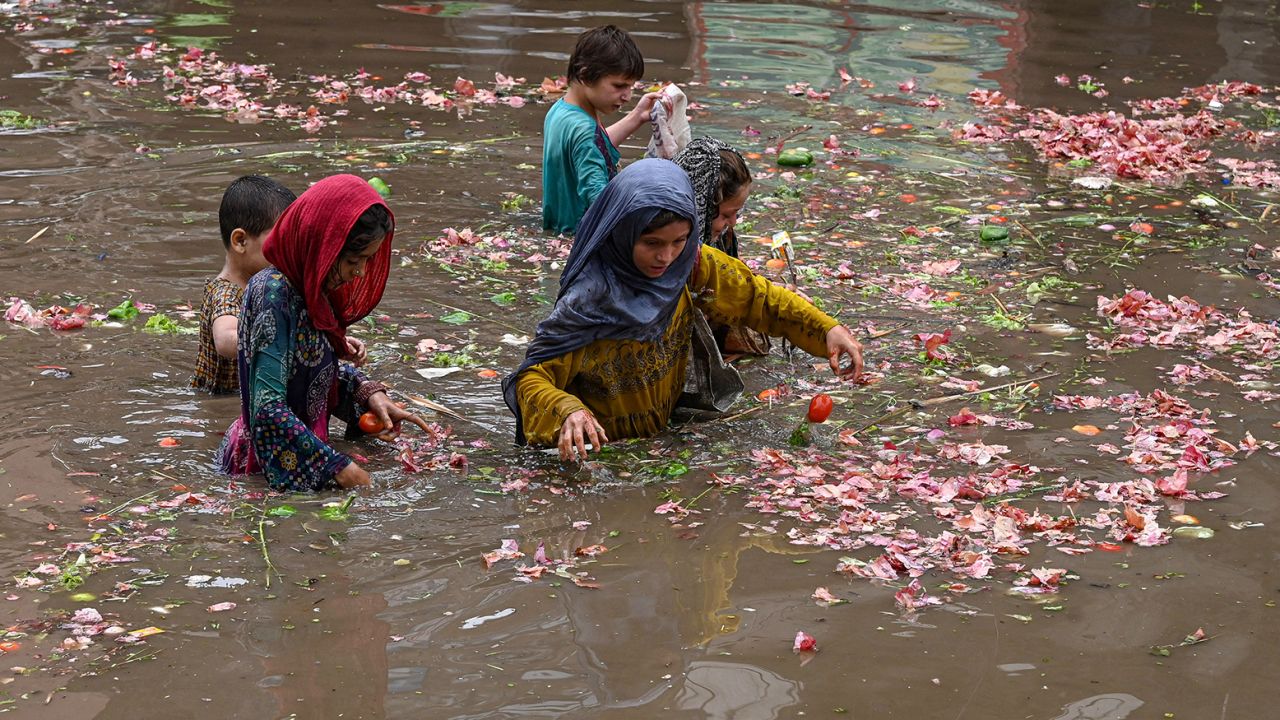 Деца берат зеленчуци от водата на наводнен пазар след проливен дъжд в Лахор на 26 юни 2023 г. 