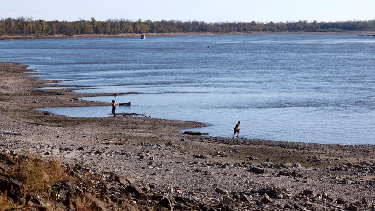 People walk along the banks of the Mississippi River, which has seen record low water levels, in Grand Tower, Illinois, November 2, 2022.