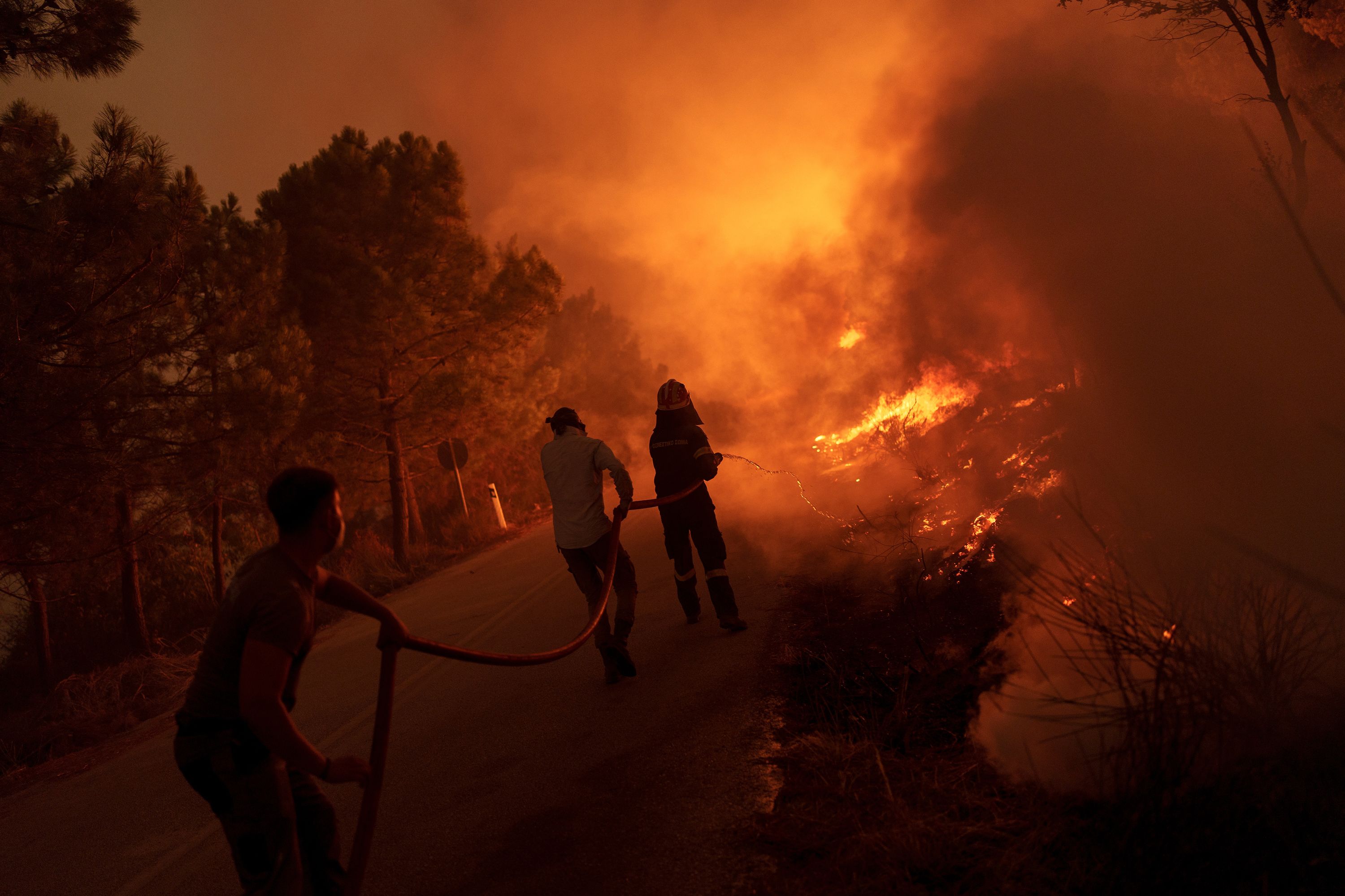 Firefighters and volunteers work to extinguish a wildfire near the village of Dikella, west of Alexandroupolis, Greece, on Tuesday, August 22.