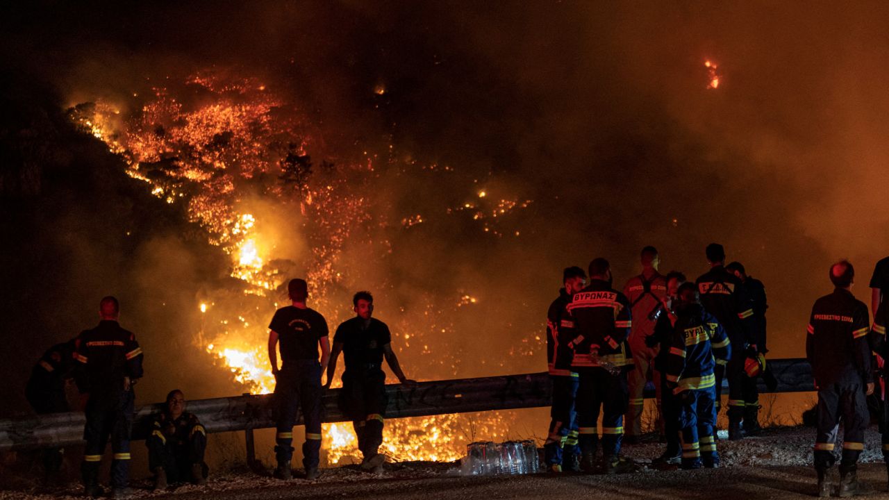 Firefighters look at a wildfire burning on Mount Parnitha, in Athens, Greece, August 24, 2023. 