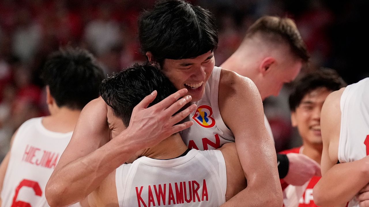 Japan forward Yuta Watanabe (12), center back, and guard Yuki Kawamura (5) hug as they celebrate defeating Finland in the Basketball World Cup group E match in Okinawa, southern Japan, Sunday, August 27, 2023. 