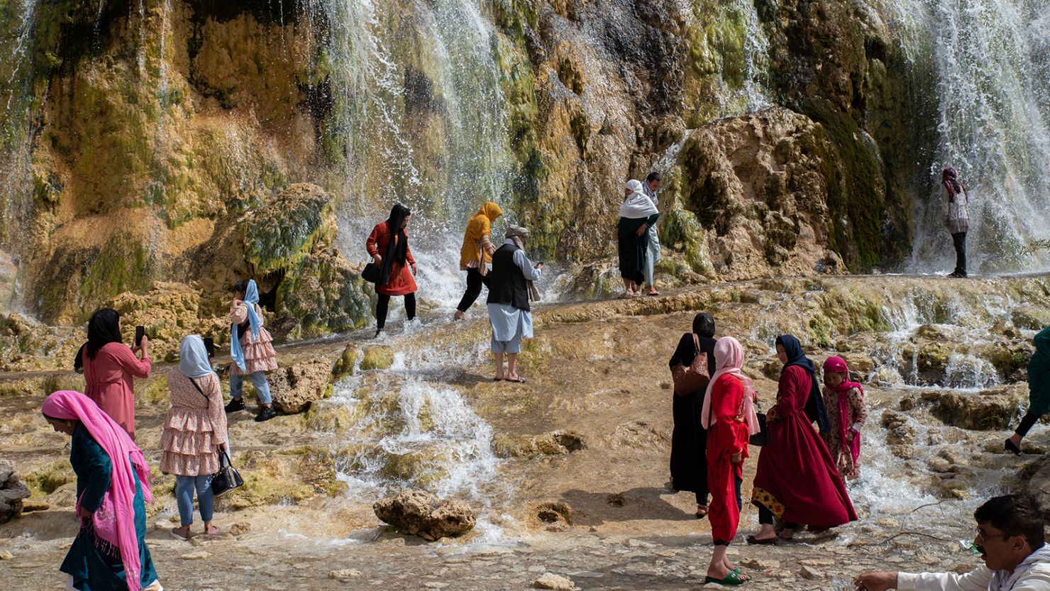 Afghan women walk by a waterfall in the Band-e Amir National Park on August 12, 2022. 