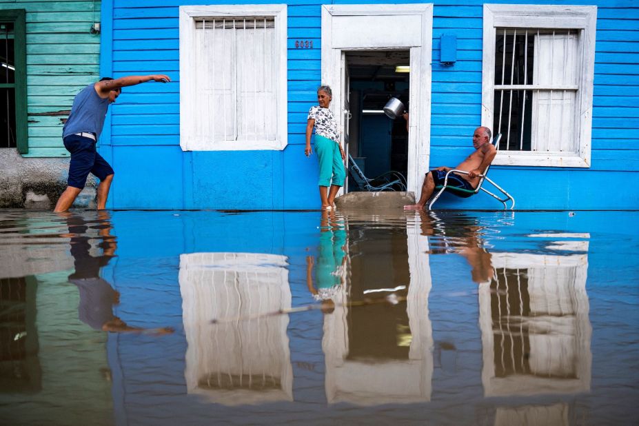 A couple is seen outside their house in a flooded area of Batabanó, Cuba, on Monday, August 28.