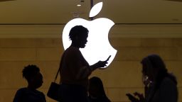 A women uses an iPhone mobile device as she passes a lighted Apple logo at the Apple store at Grand Central Terminal in New York City, U.S., April 14, 2023. REUTERS/Mike Segar
