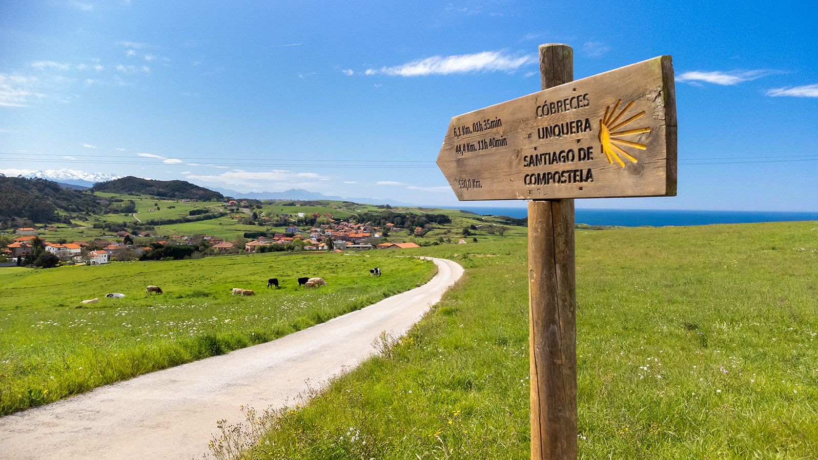 Wooden milestone indicating kilometers to Unquera and Cobreces during the route of the Camino de Santiago. no people