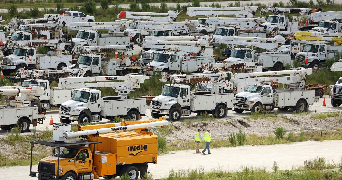 Electrical line technicians walk among hundreds of trucks at Duke Energy's staging location in Sumterville, Florida, on August 29.
