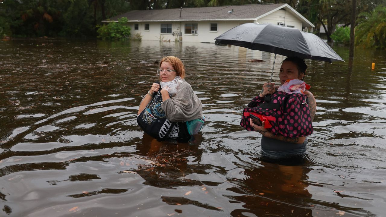 Magadla Richter, left, and her mother Kayfra Laine wade through floodwaters Wednesday in Tarpon Springs, Florida.