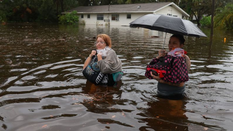 Makatla Ritchter, left, and her mother, Keiphra Line, wade through floodwaters after having to evacuate their home in Tarpon Springs on August 30.